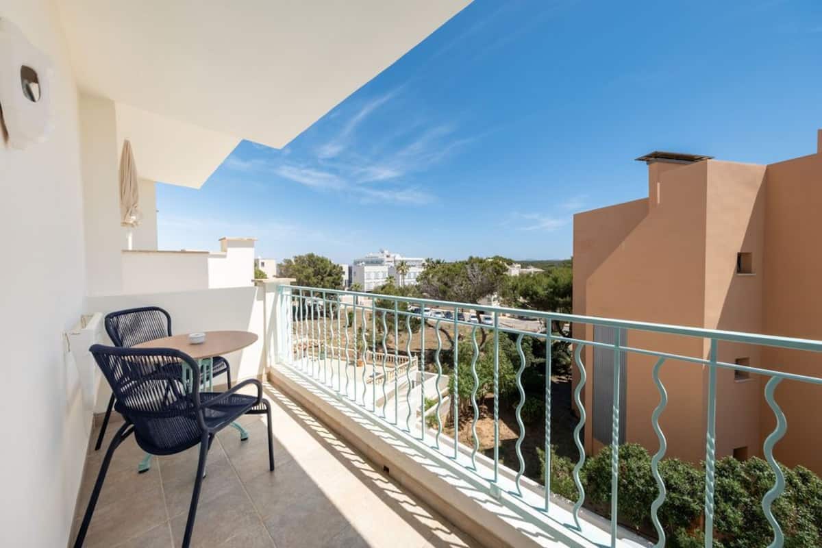 A balcony with a table and chairs, a view of the city, and a railing.