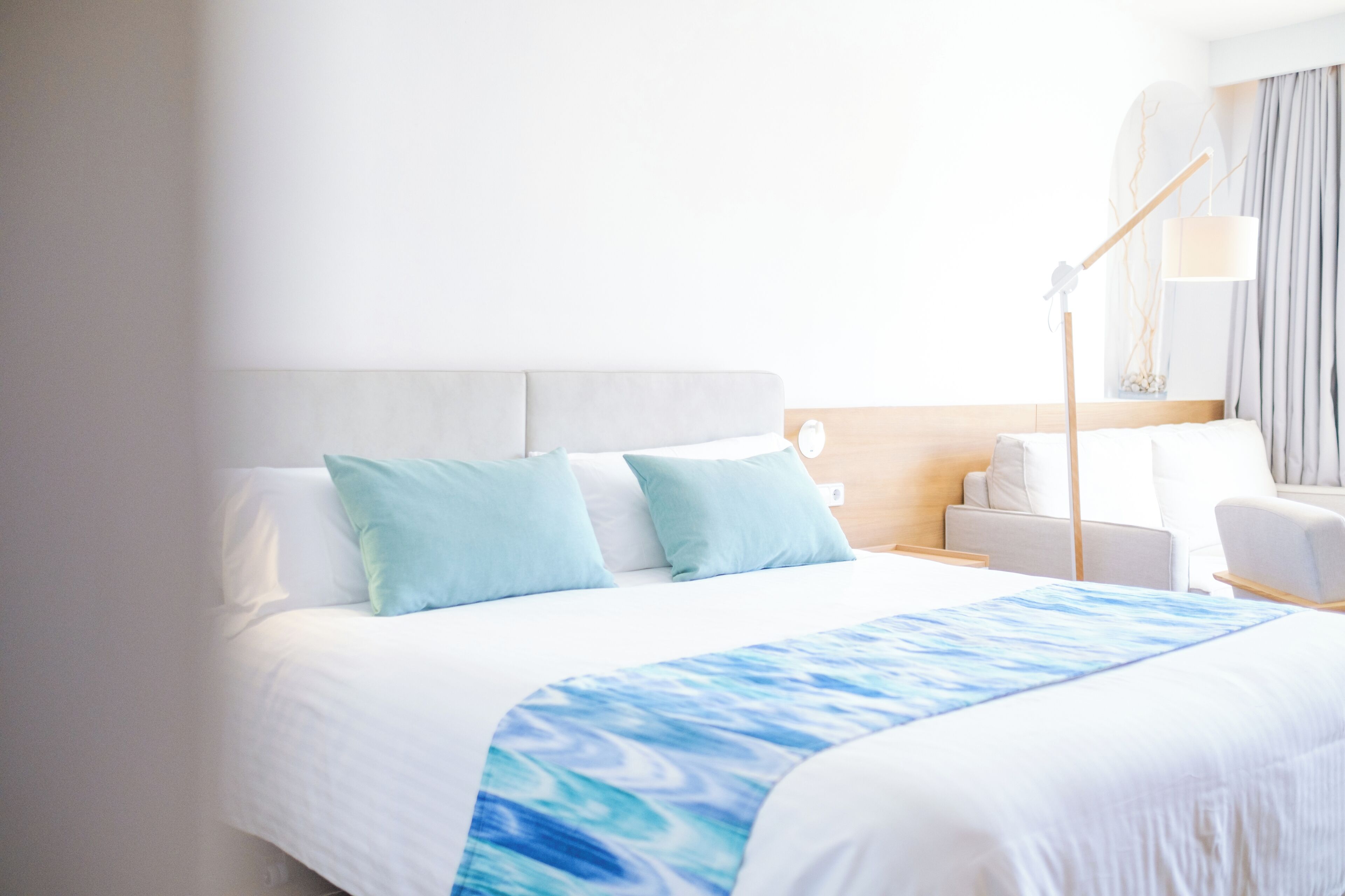 Een hotelkamer met een bed, nachtkastje, lamp en stoel.