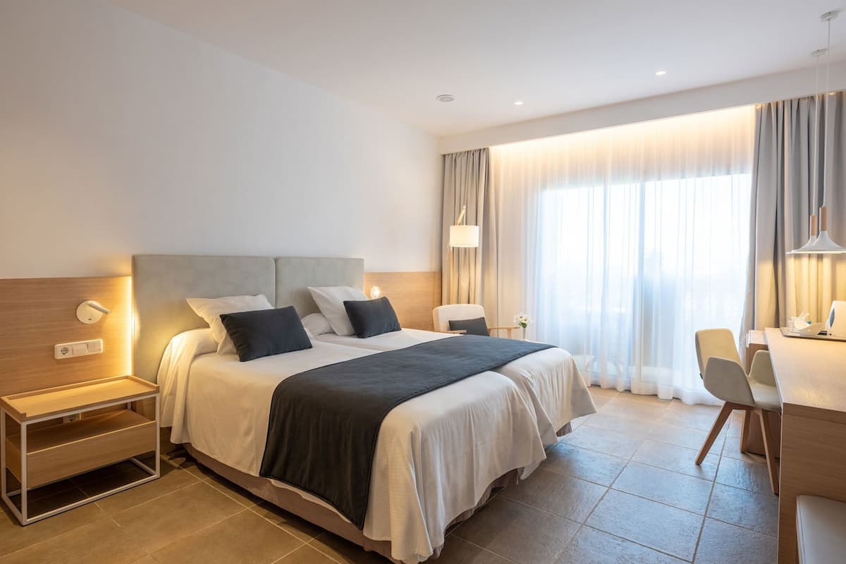A hotel room with a large bed, bedside tables, a desk, and a chair.