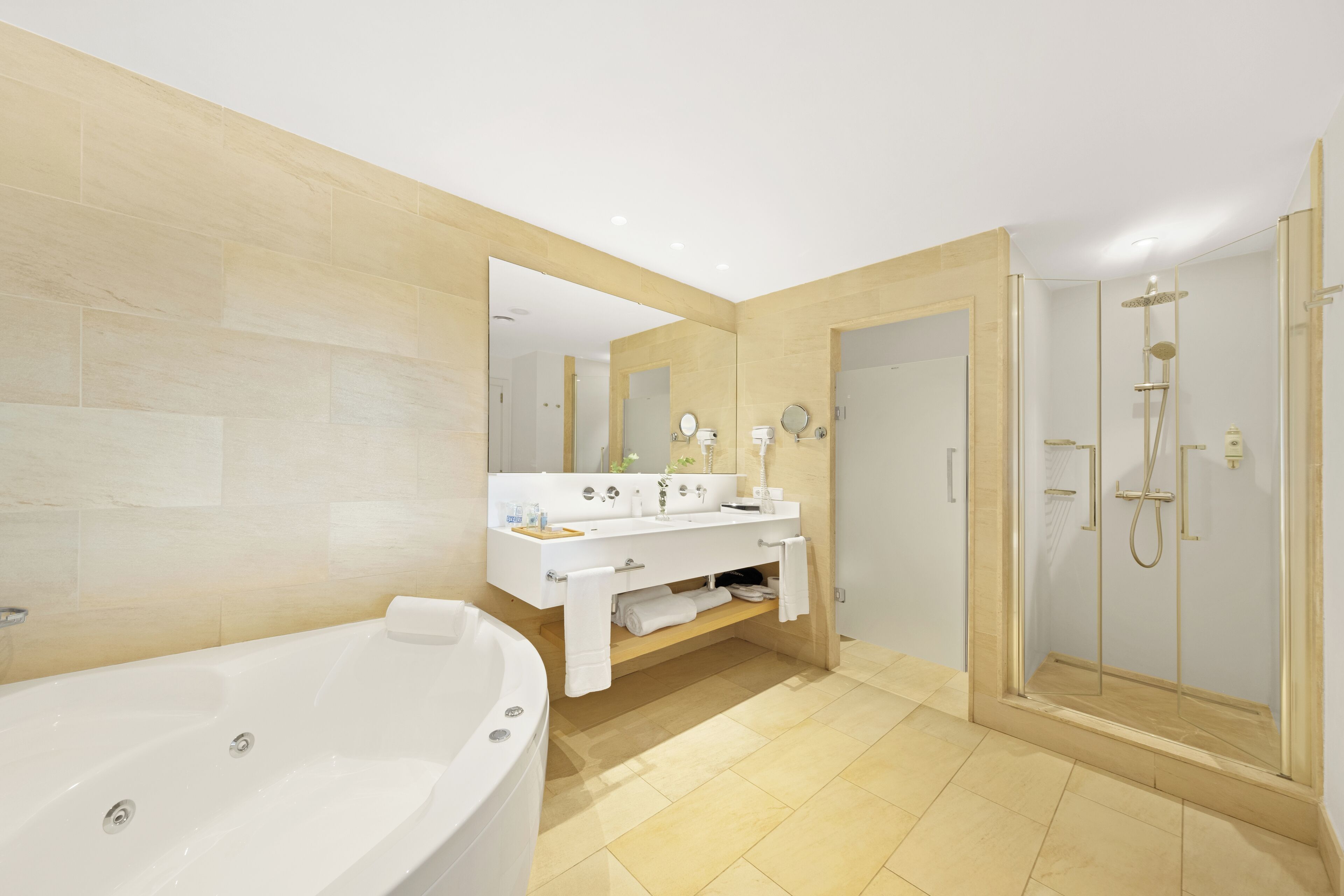 Ein modernes Badezimmer mit einer großzügigen Badewanne, einem Doppelwaschtisch und einer begehbaren Dusche, sowie einem Spiegel über dem Waschtisch.