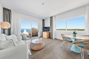 Un salón amplio con un sofá, sillas, una mesa de centro redonda, un televisor y una mesa de comedor con sillas.