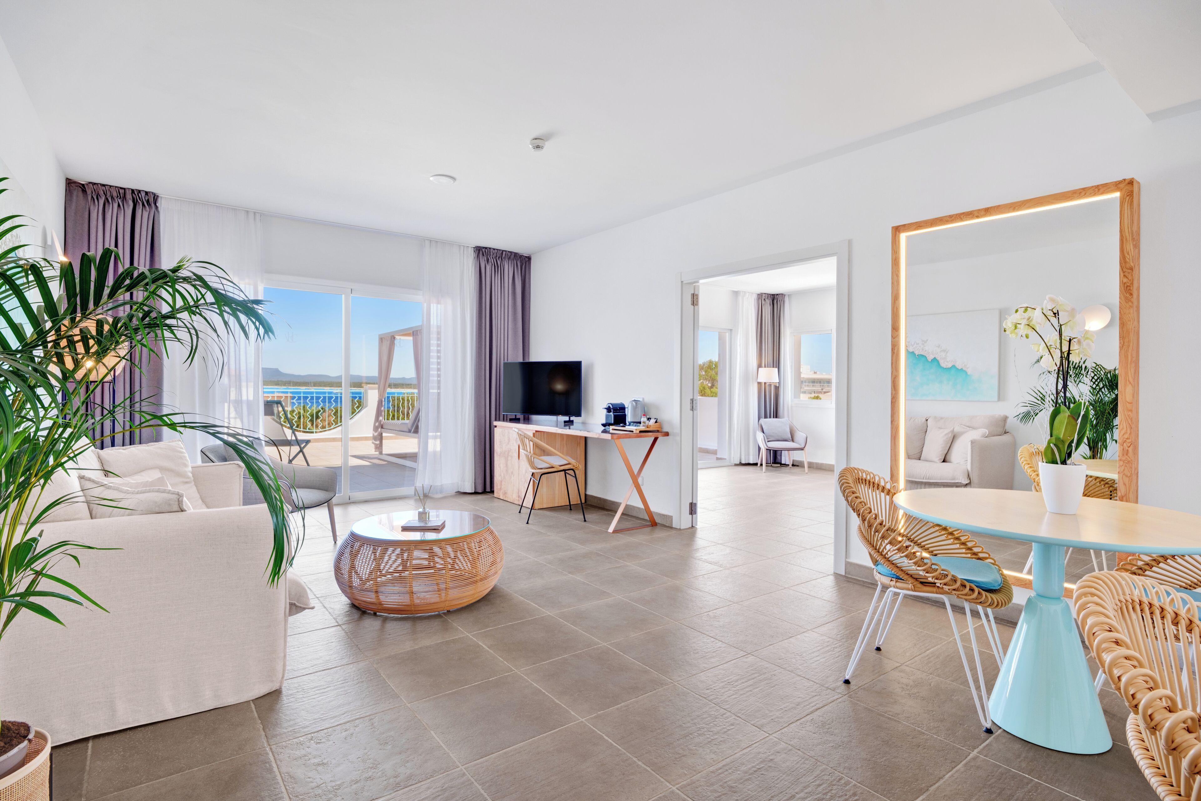 Una habitación de hotel moderna con balcón, comedor y zona de estar.