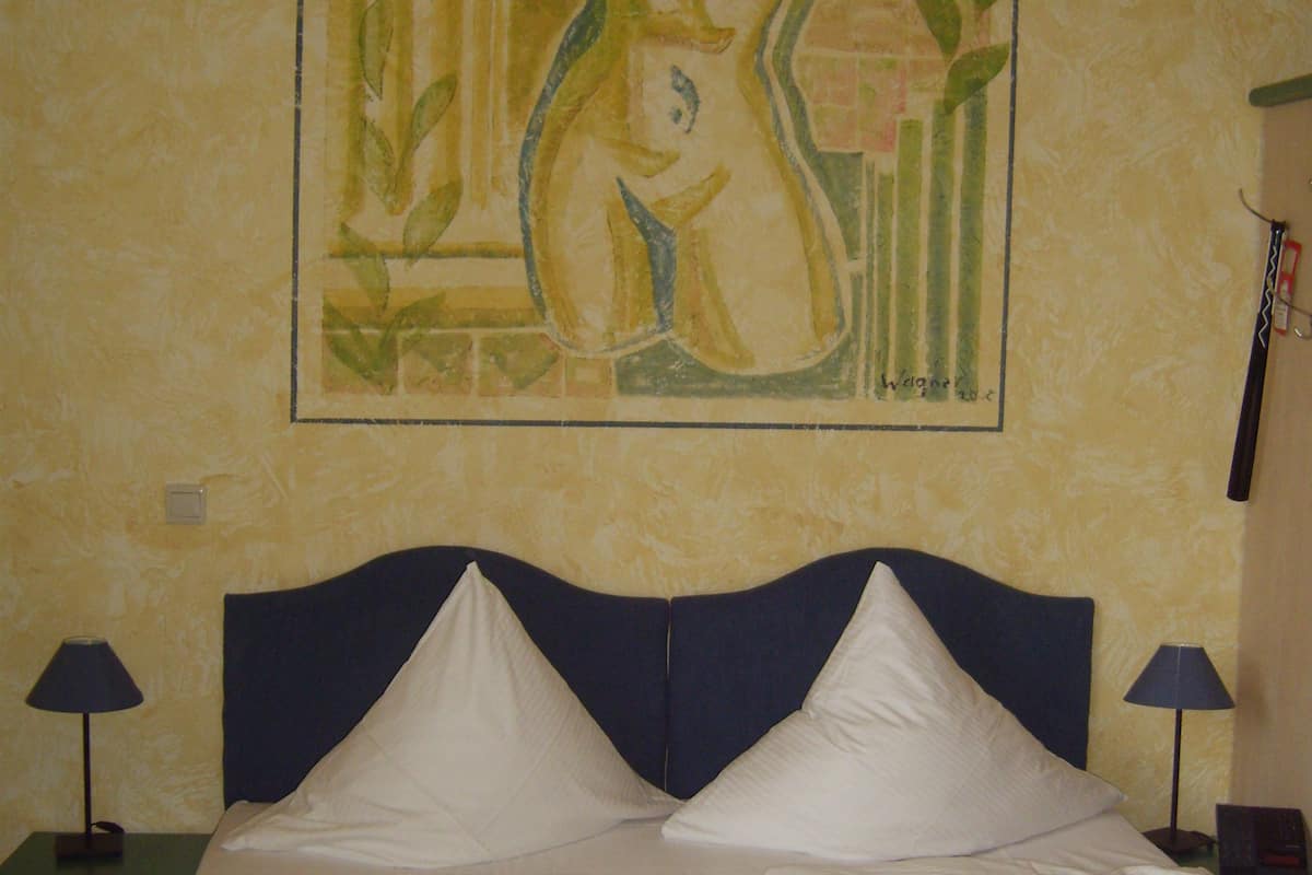 Ein Hotelzimmer mit einem Bett, zwei Nachttischlampen und einem Gemälde an der Wand.
