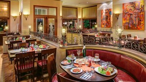 Un restaurante con varias zonas de comedor, incluyendo un banco central y varias mesas con sillas.