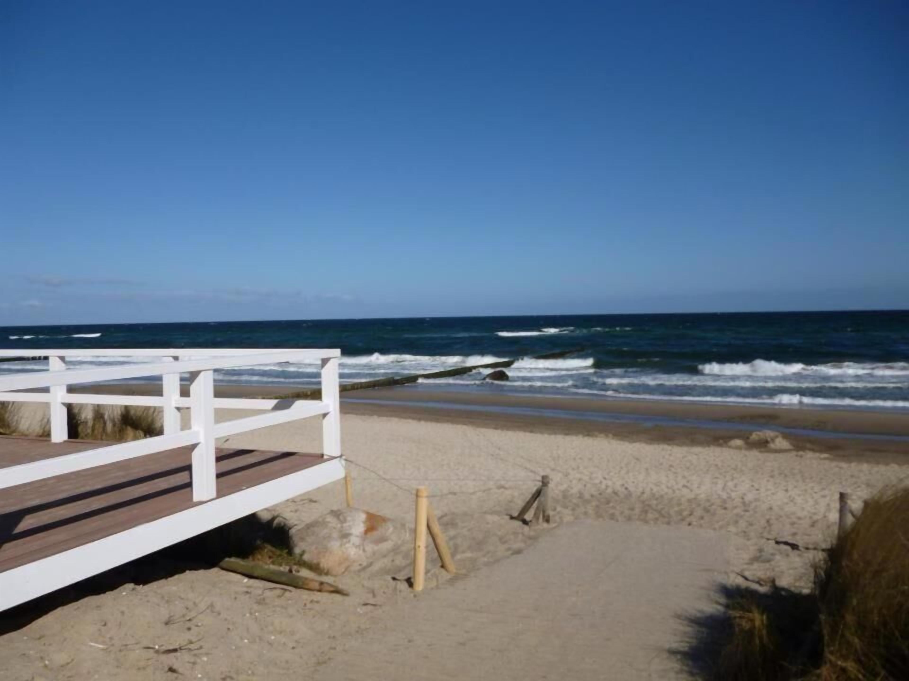 A beach with a white wooden walkway leading to the shore.