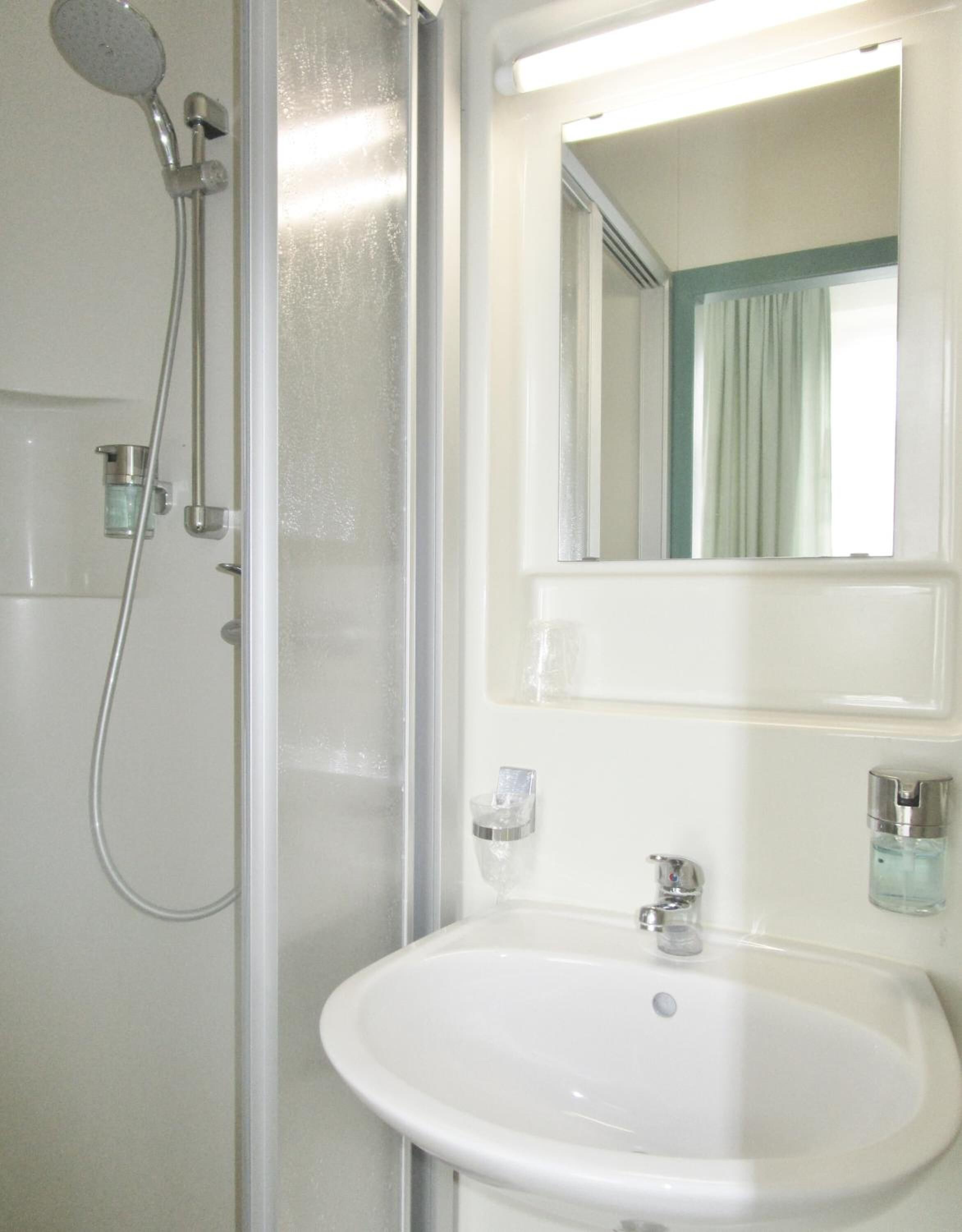 A bathroom with a shower, sink, and mirror.