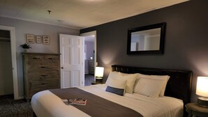 A neatly made bed with a dark headboard, a dresser with multiple drawers, and a mirror on the wall. - Little Fig Hotel (Bar Harbor)