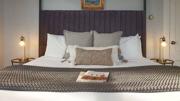 A neatly made bed with a headboard, two bedside lamps, and a framed picture above.