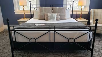 Una cama con estructura metálica negra, un tapete estampado y dos lámparas de noche.