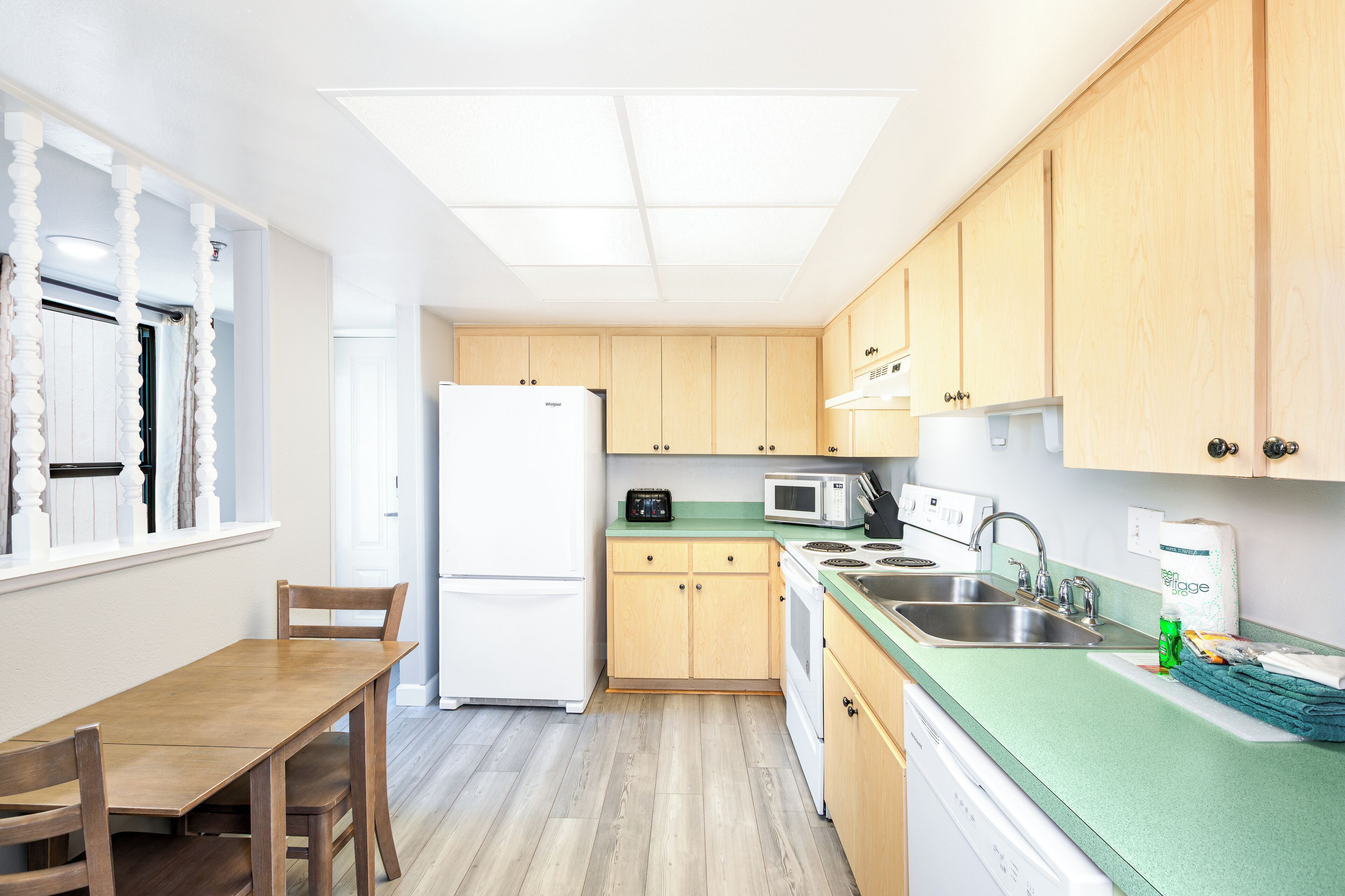 A compact kitchen with wooden cabinets, a white refrigerator, a microwave, and a sink.