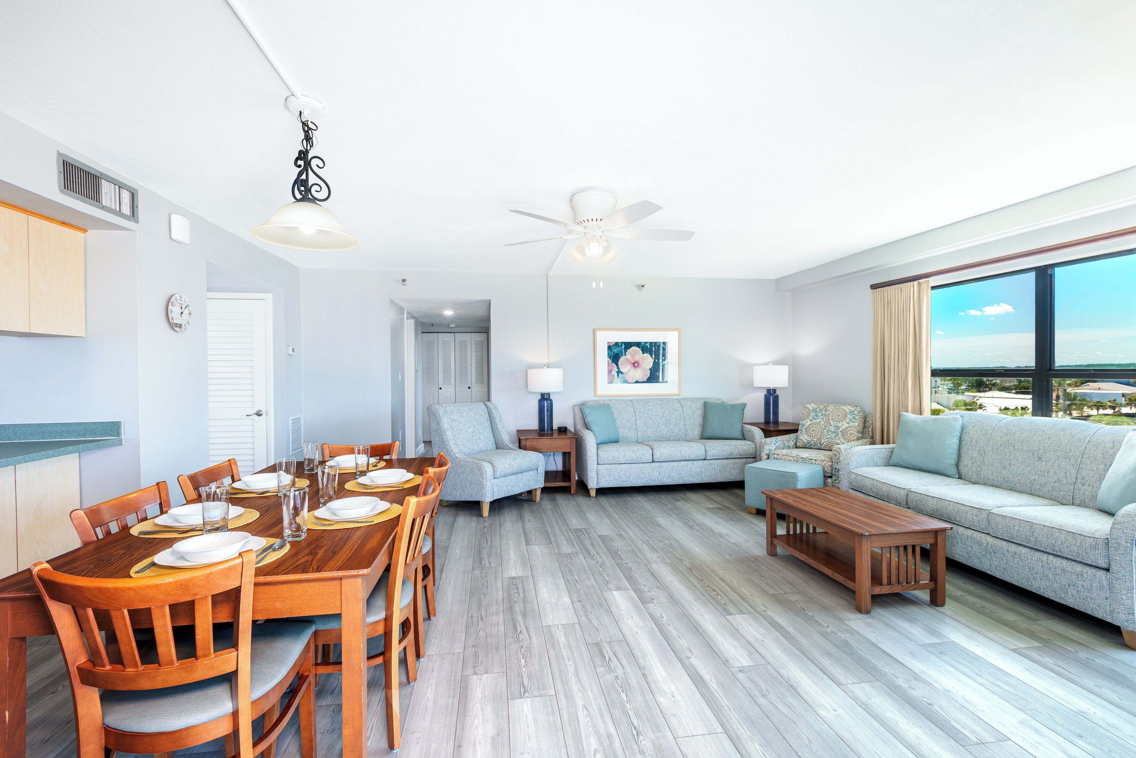 A spacious living room with a dining area, a sofa set, and a view of the outdoors.