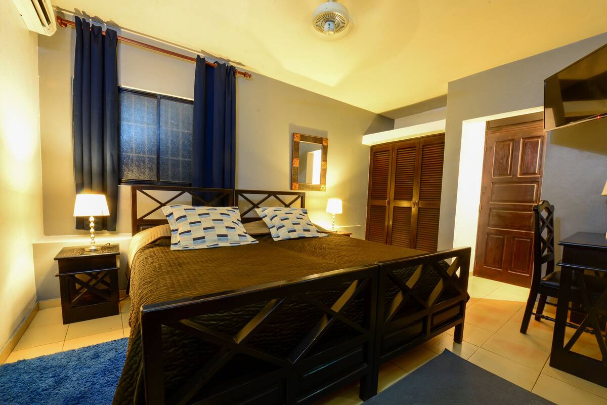 Une chambre à coucher comprenant un lit, des tables de chevet, un bureau et une armoire.