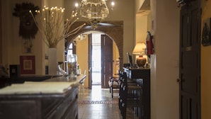 A hallway with a chandelier, a wooden table, and a door. - Casa Naemie (Santo Domingo)