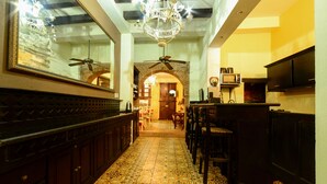 A hallway with patterned flooring, a ceiling fan, a chandelier, and a large mirror on the left. - Casa Naemie (Santo Domingo)