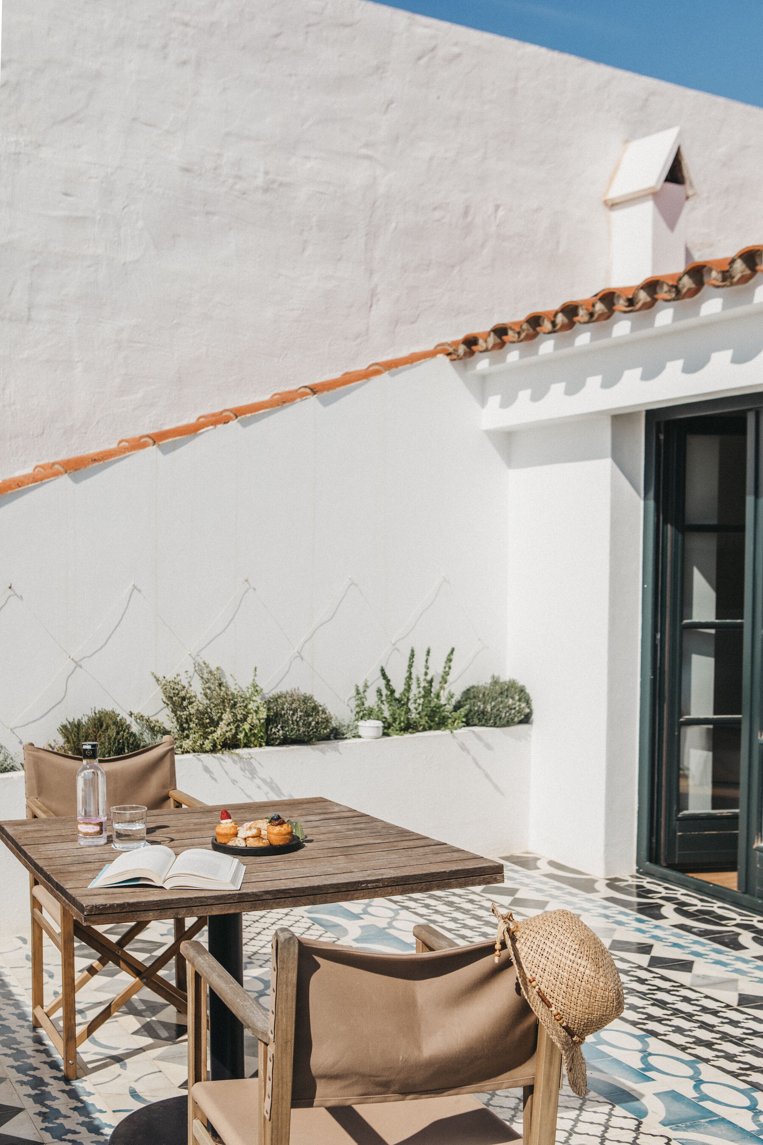 An outdoor seating area with a table, chairs, and a small garden.
