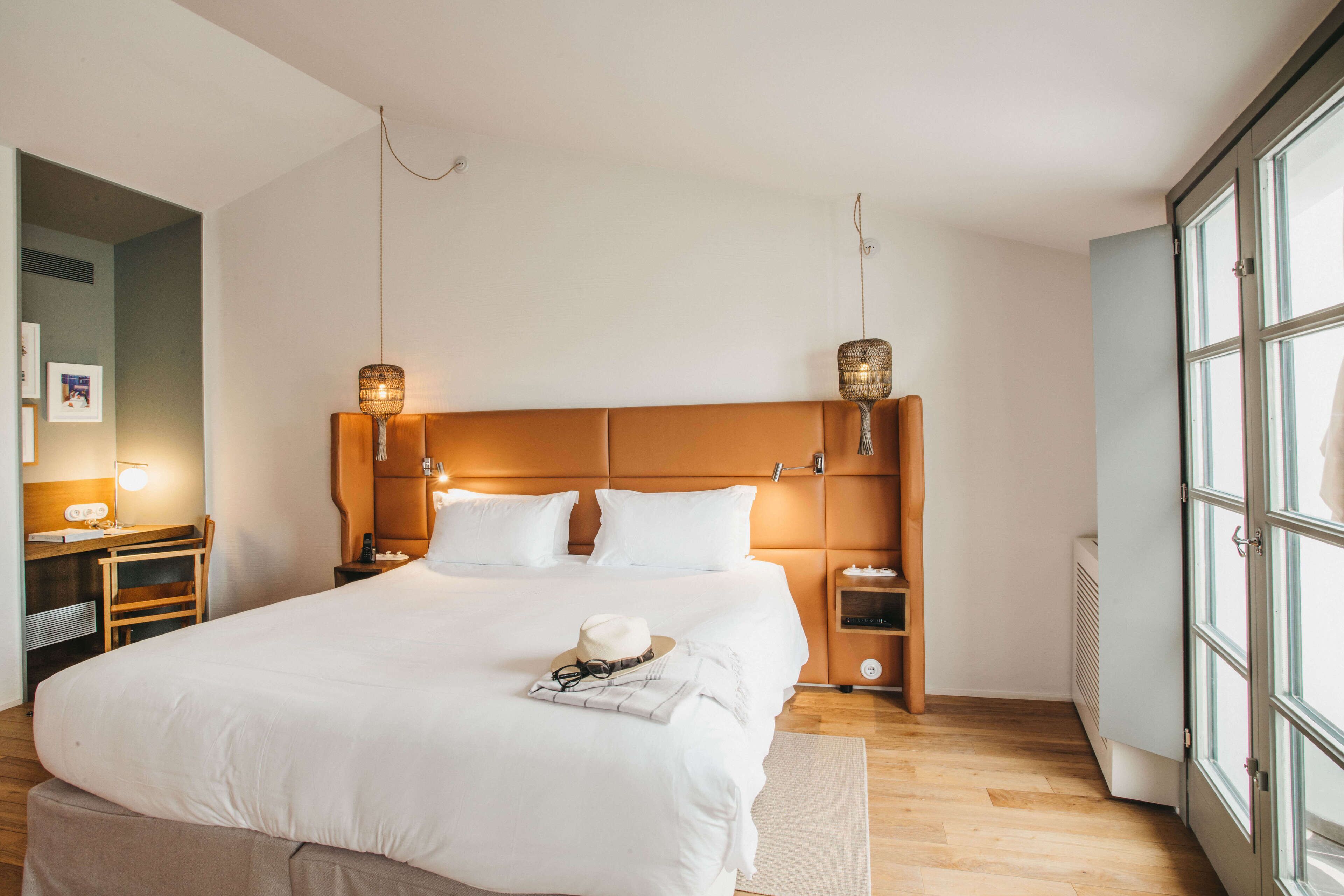 Una habitación de hotel moderna con una cama grande, mesitas de noche, un escritorio y una ventana.