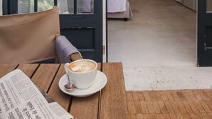 Una habitación acogedora con una mesa de madera, una taza de café y vistas a un dormitorio a través de una puerta abierta.