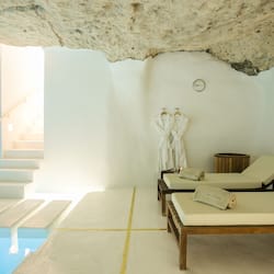 Relax in a serene spa room with a large glass pool and comfortable lounge chairs.
