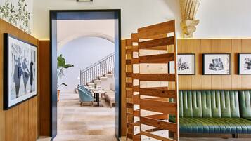 Un pasillo con un banco de madera, una escalera y cuadros en las paredes.