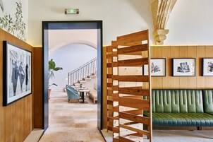 Un pasillo con un banco de madera, una escalera y cuadros en las paredes.
