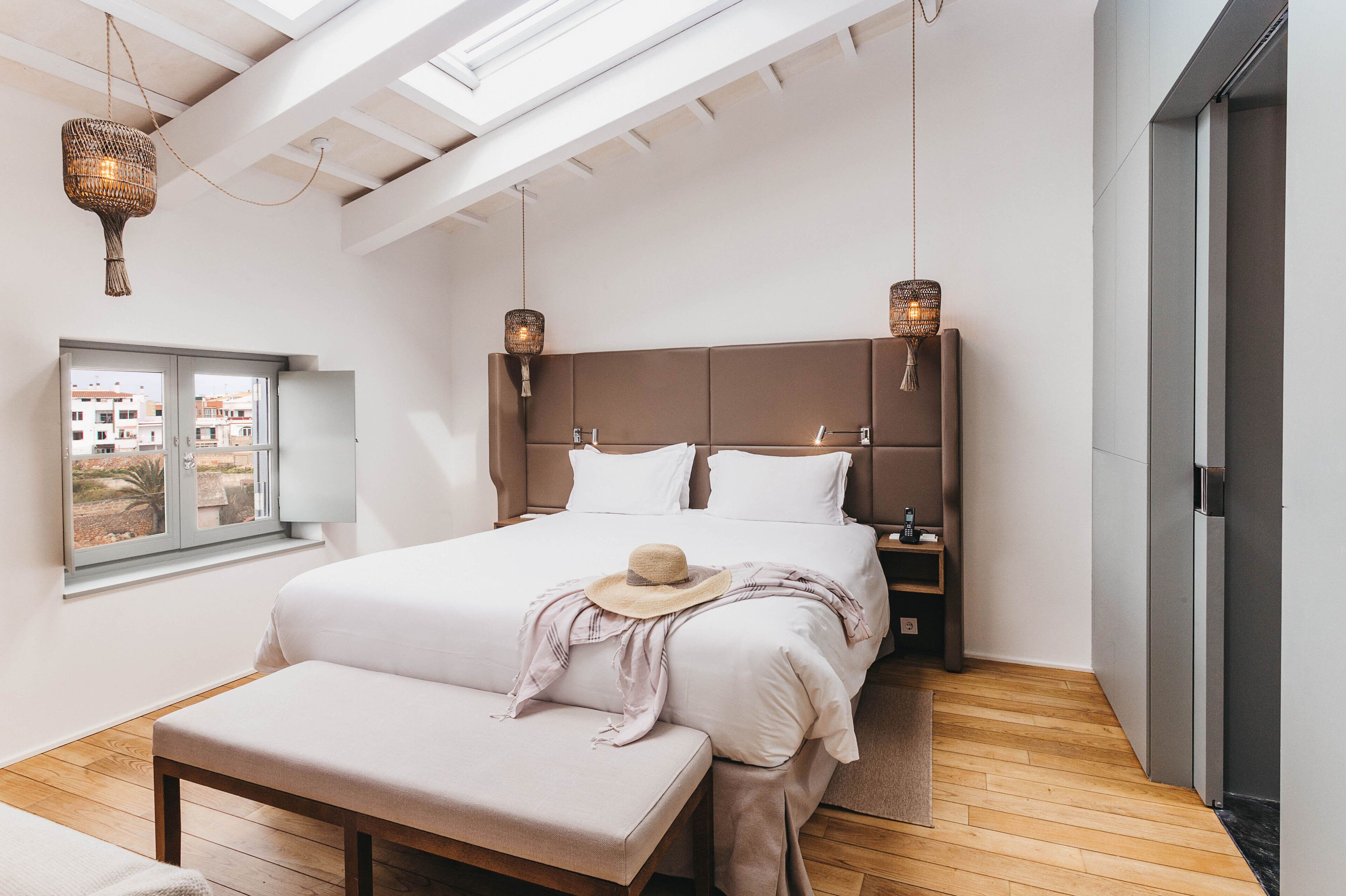 Ein modernes Schlafzimmer mit einem großen Bett, einer Bank, einem Fenster mit Blick und zwei Nachttischlampen.