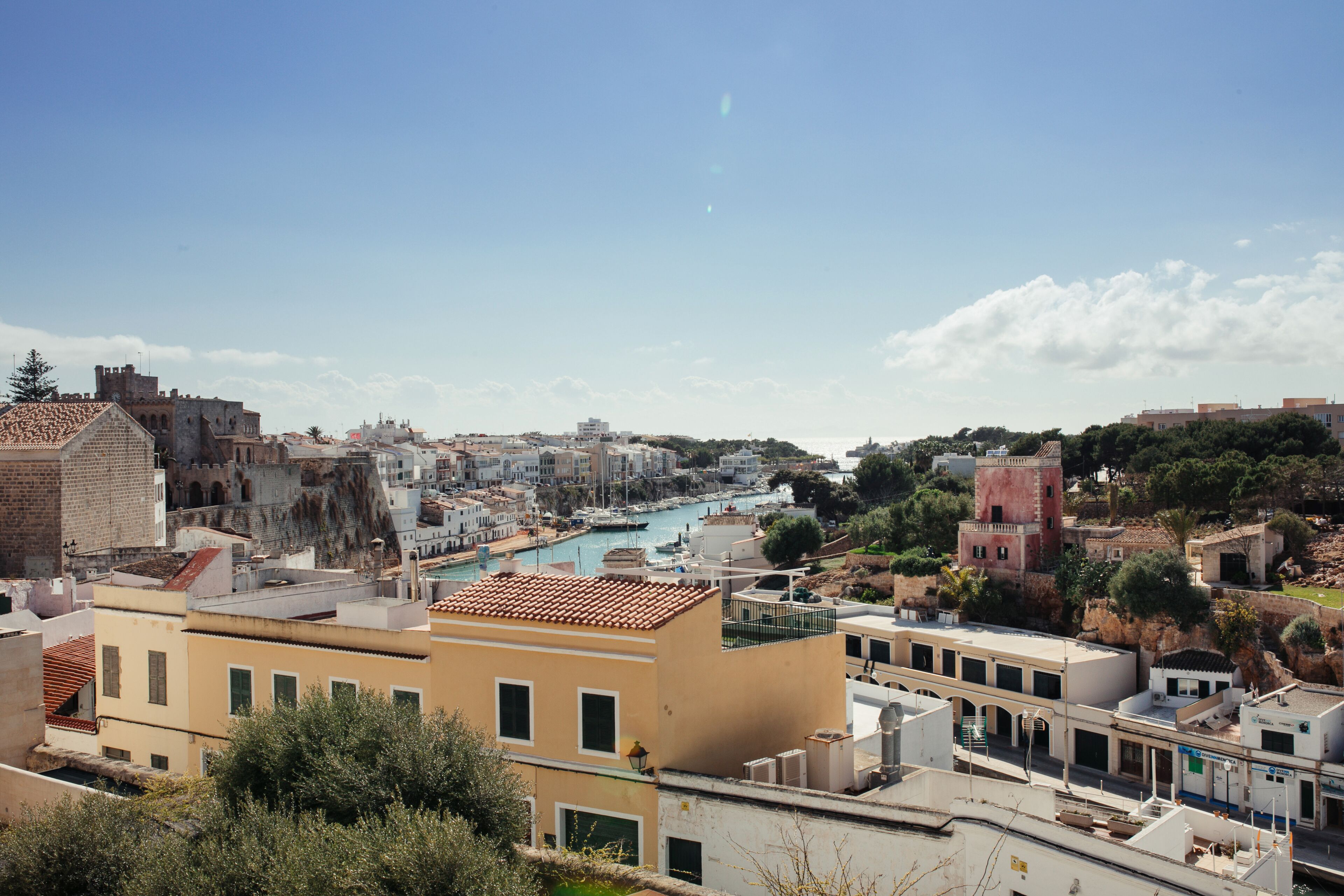 Un paisaje costero con edificios históricos, un puerto deportivo y un cielo despejado.