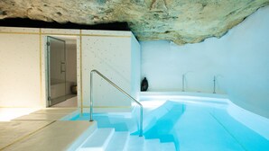 Un área de spa con un jacuzzi, ducha y una escalera que conduce a una puerta.