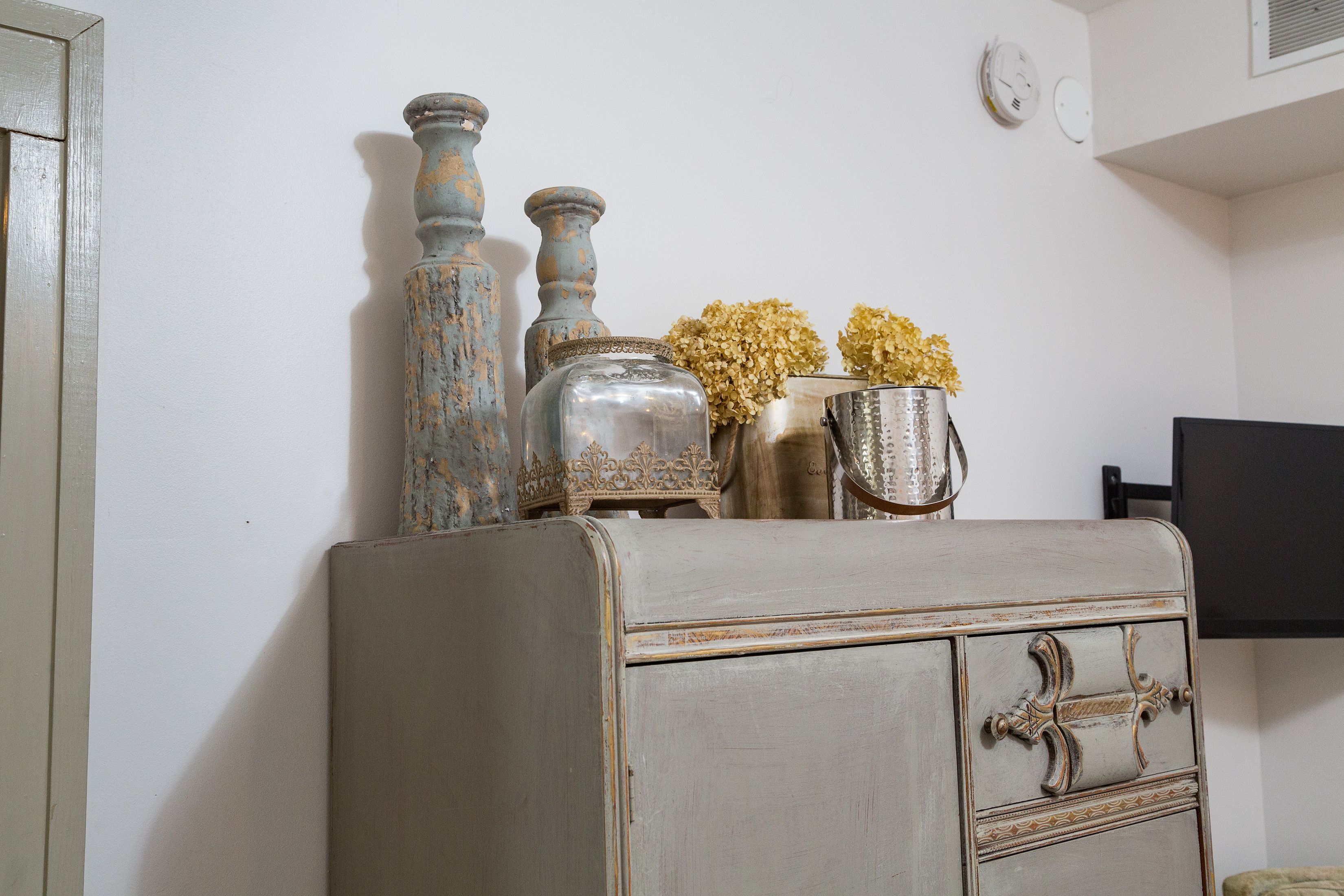 A vintage dresser with decorative vases and flowers.