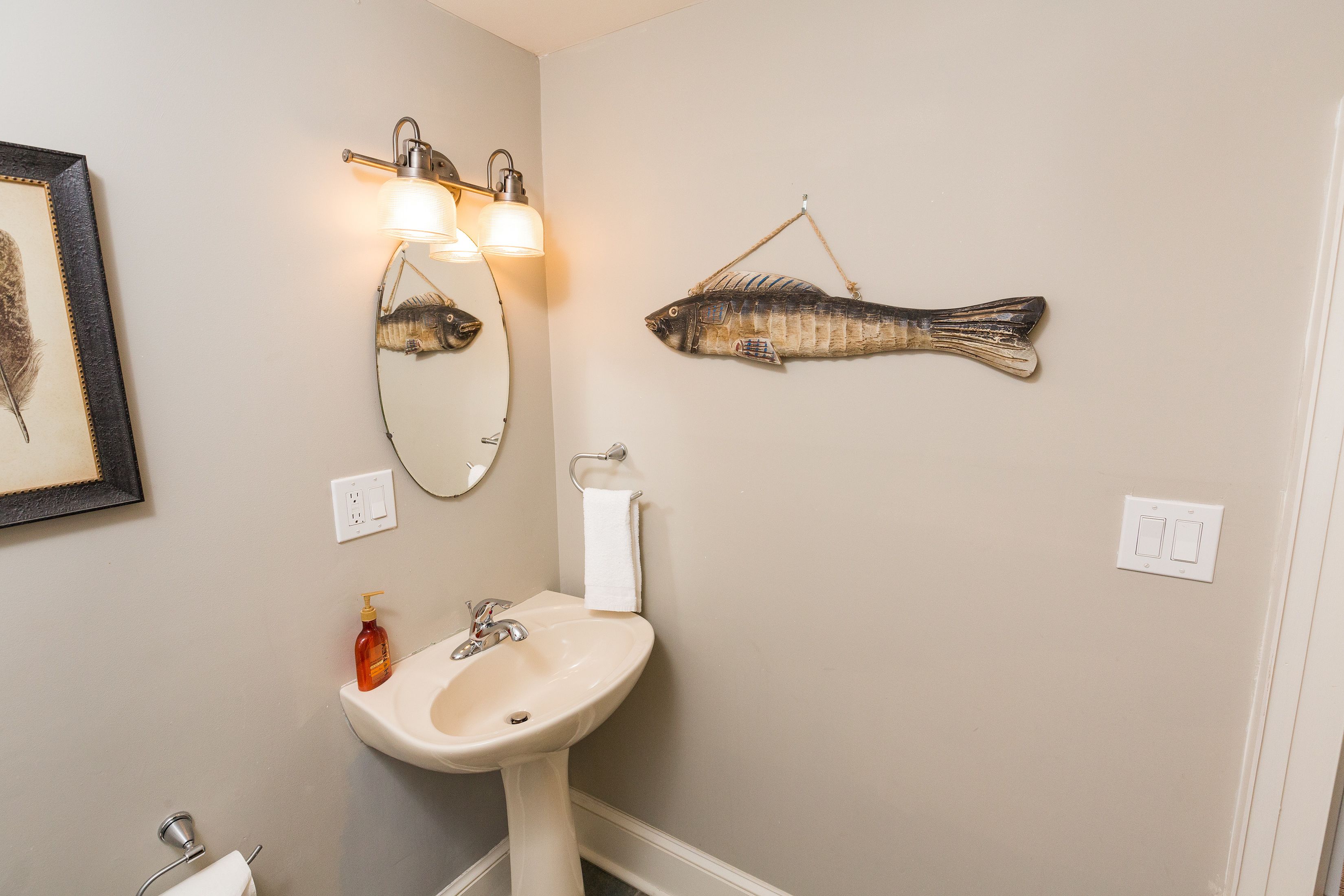 Un baño con lavamanos, espejo y dos luces empotradas.