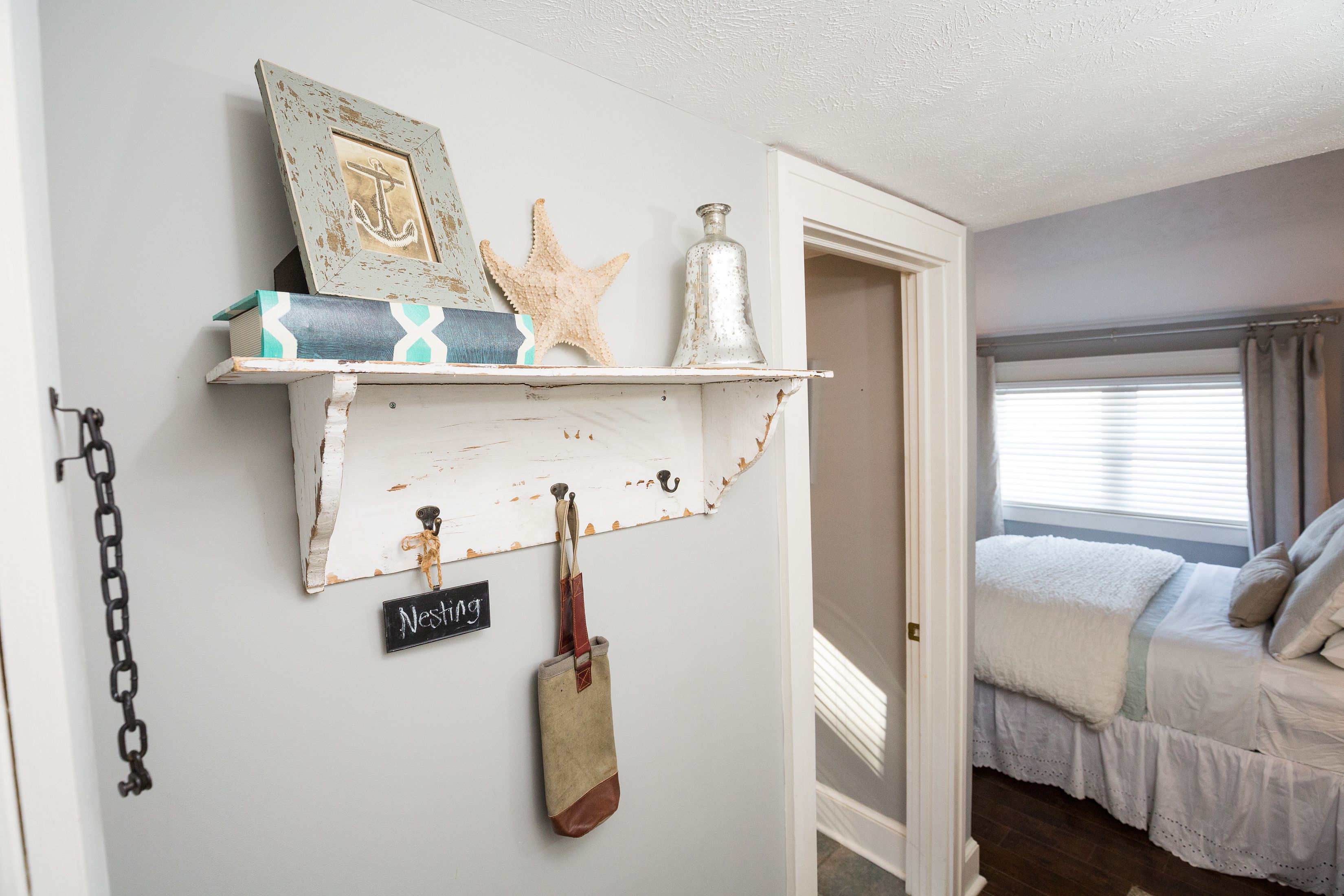 Ein Schlafzimmer mit einem Bett, einem Regal mit Dekoration und einem Schild mit der Aufschrift 'Nesting'.