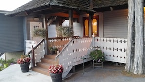 A wooden porch with a staircase, potted plants, and a sign indicating a bar. - The Nest on Saratoga Lake (Saratoga Springs)