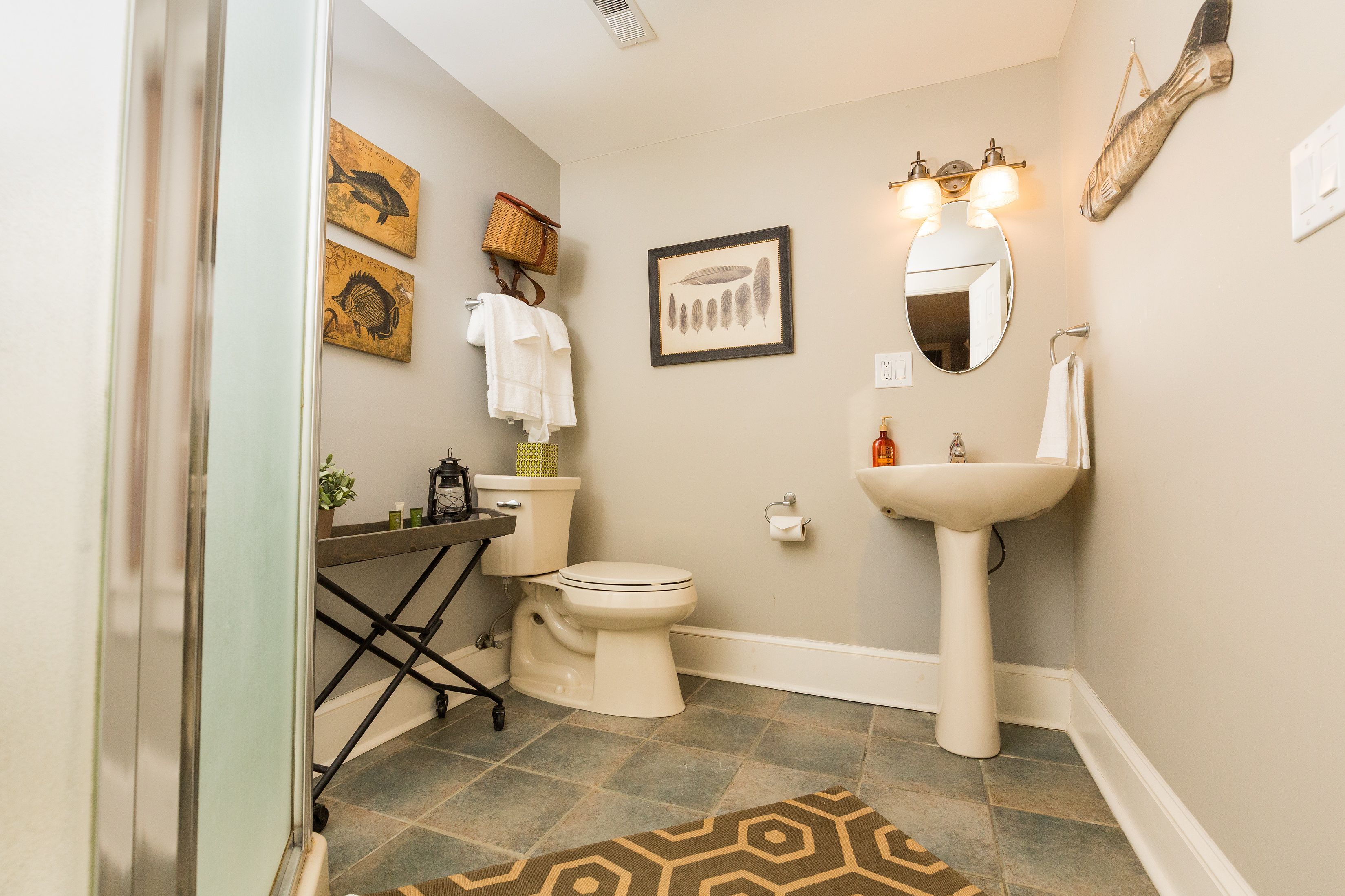A bathroom with a toilet, sink, and two framed pictures on the wall.