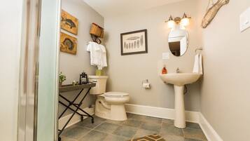 A bathroom with a toilet, sink, and two framed pictures on the wall.