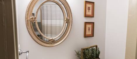 A bathroom with a round mirror, a sink, and two framed pictures on the wall.