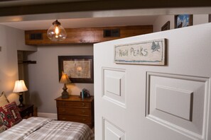 A bedroom with a bed, a dresser, a lamp, and a sign on the door. - The Nest on Saratoga Lake (Saratoga Springs)