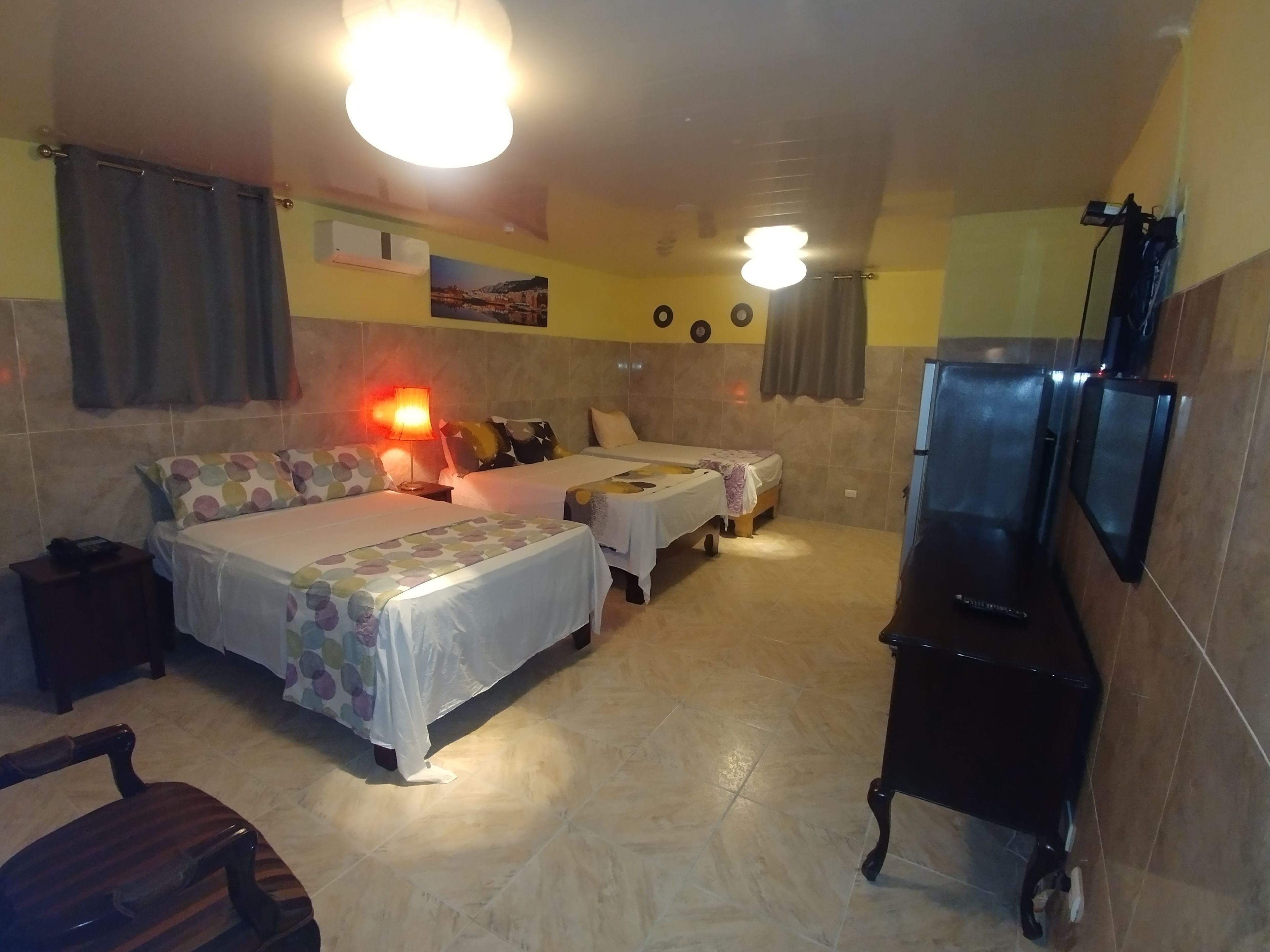 Una habitación de hotel con dos camas, televisión, escritorio y silla.