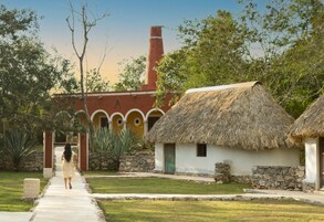 A pathway leading to a traditional building with a thatched roof and stone walls.