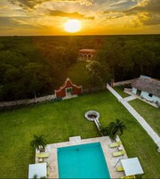 A pool with lounge chairs, a garden, and a building with arches.