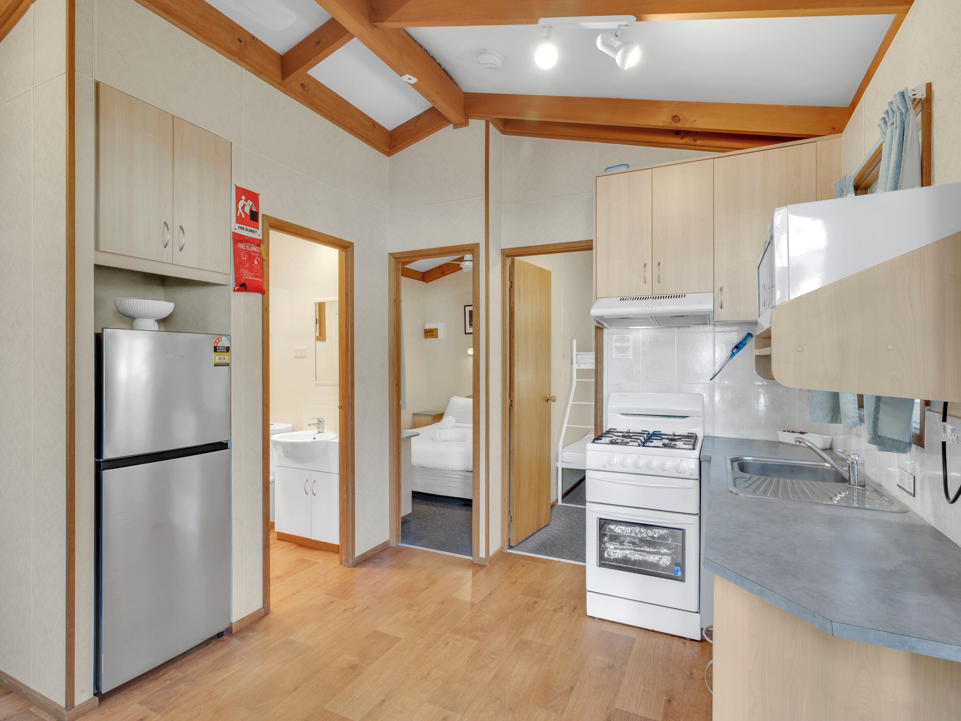 Une cuisine moderne avec des meubles en bois, un réfrigérateur en acier inoxydable, une cuisinière à gaz et un évier.