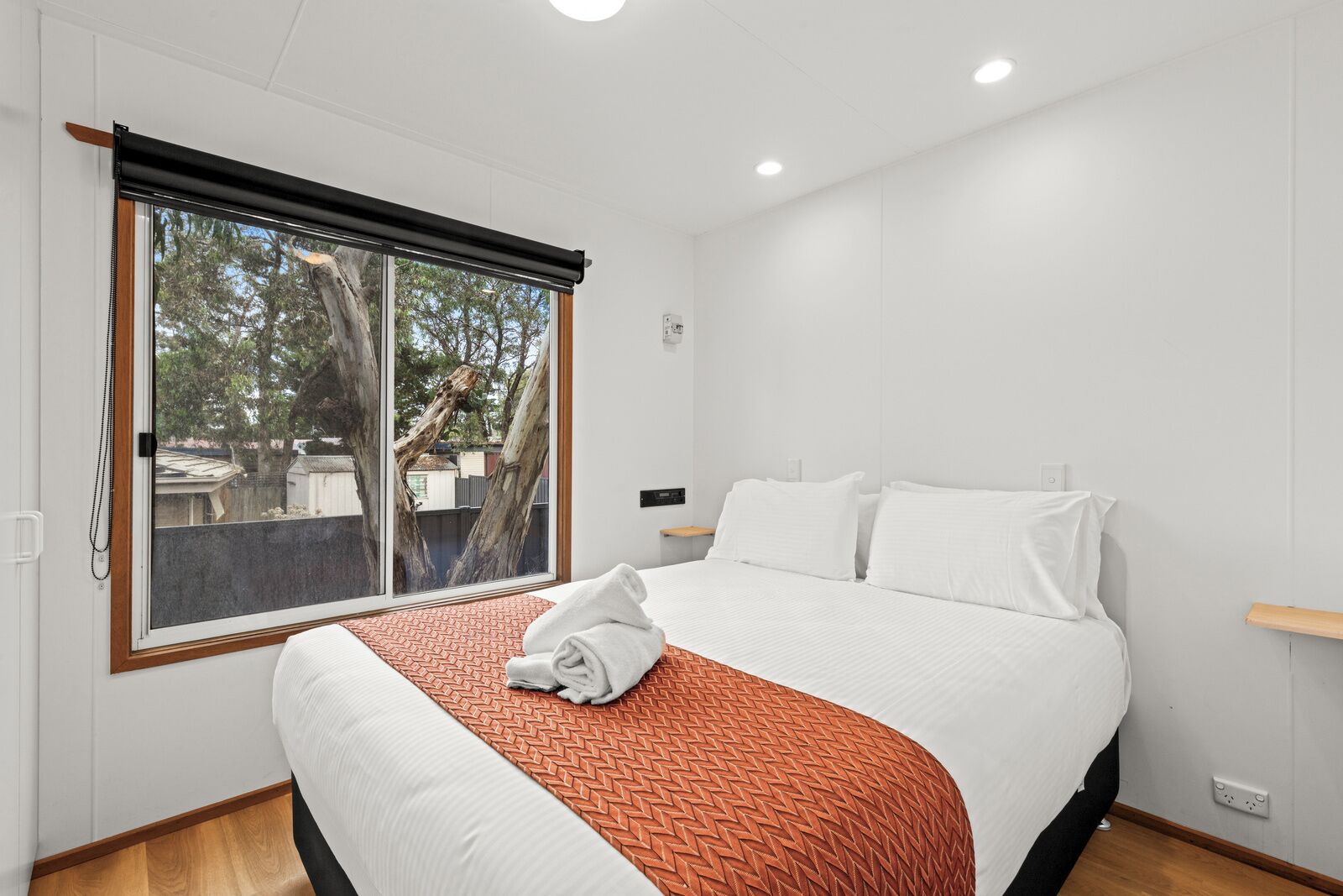 Une chambre d’hôtel avec un grand lit, une fenêtre donnant sur la verdure et un plancher en bois.