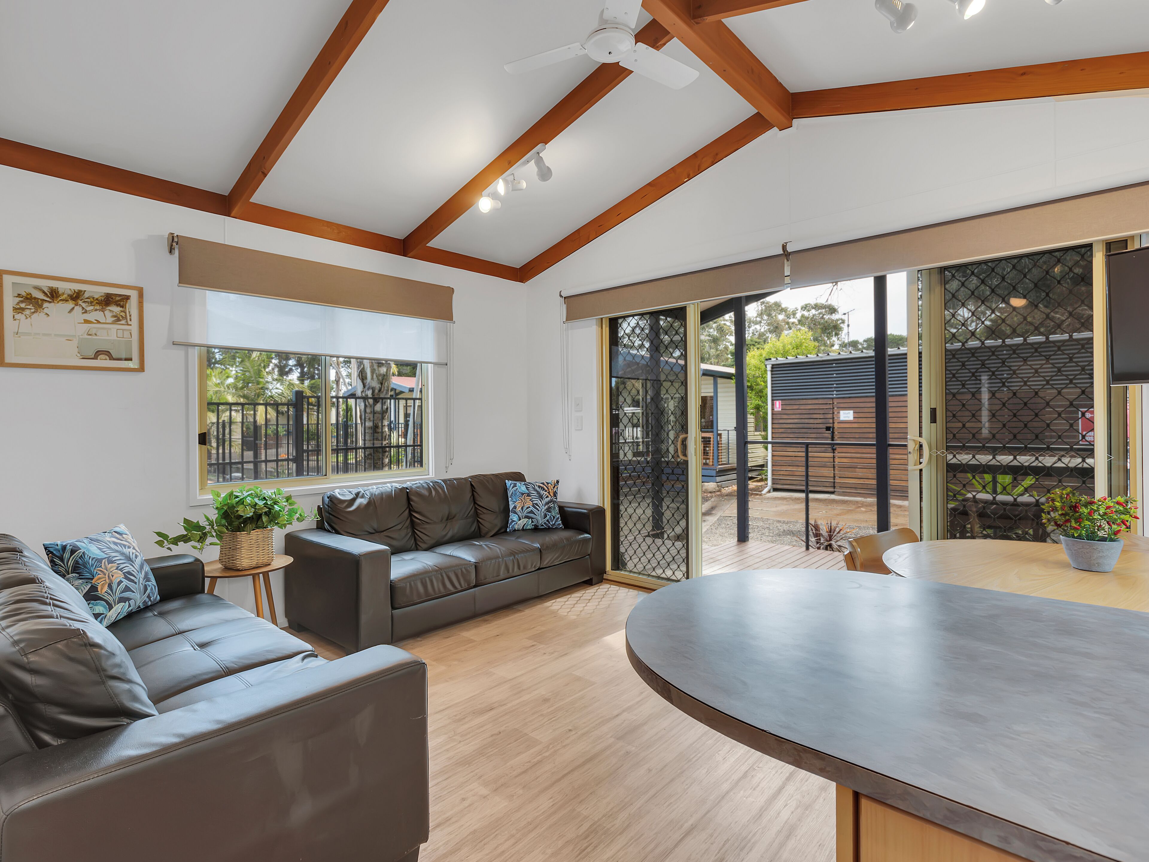 A modern living room with a leather sofa, a dining table, and a large window with a view of the outside.