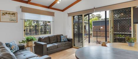 A modern living room with a leather sofa, a dining table, and a large window with a view of the outside.