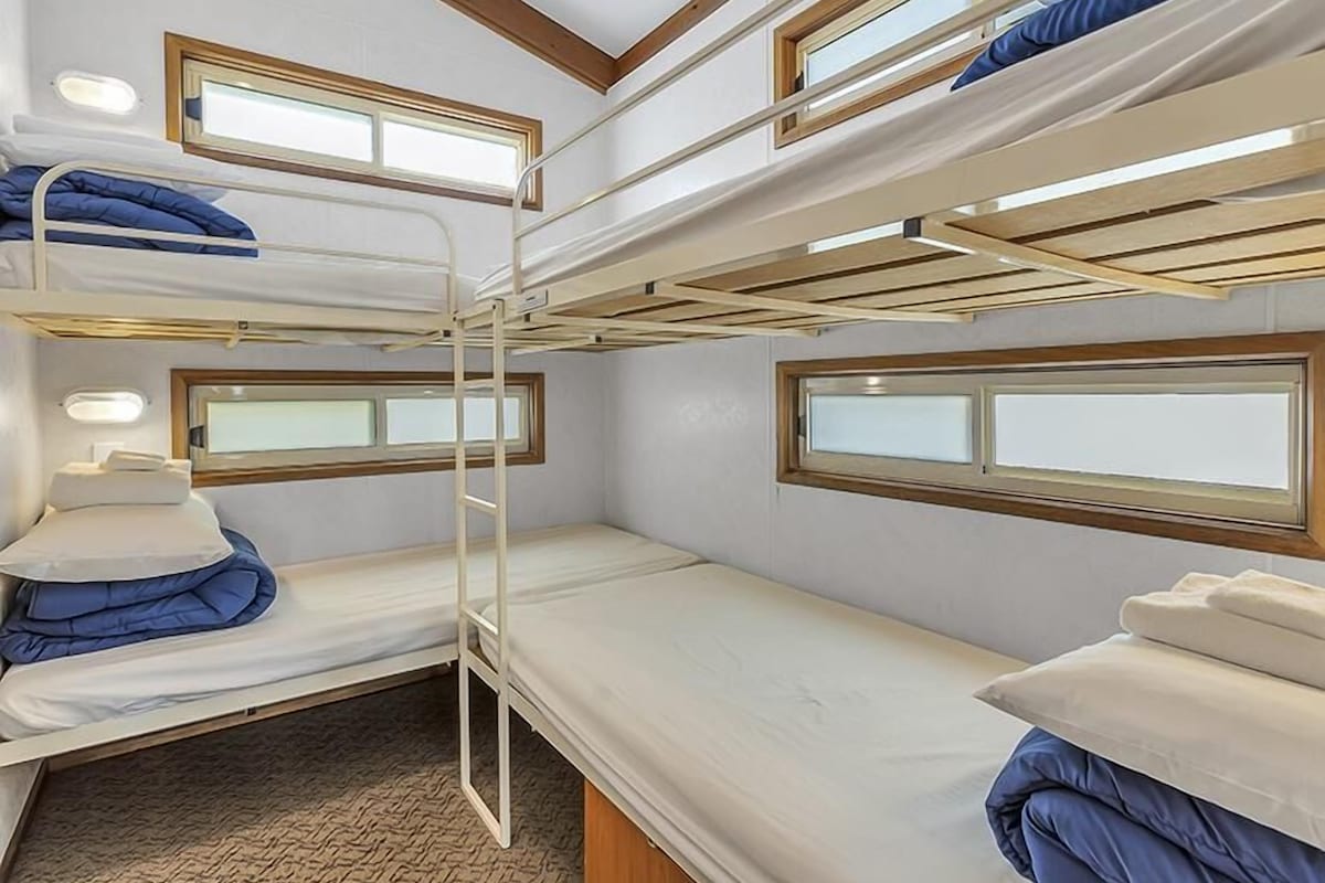 Habitación con literas, tres camas, cada una con ventana y escalera.