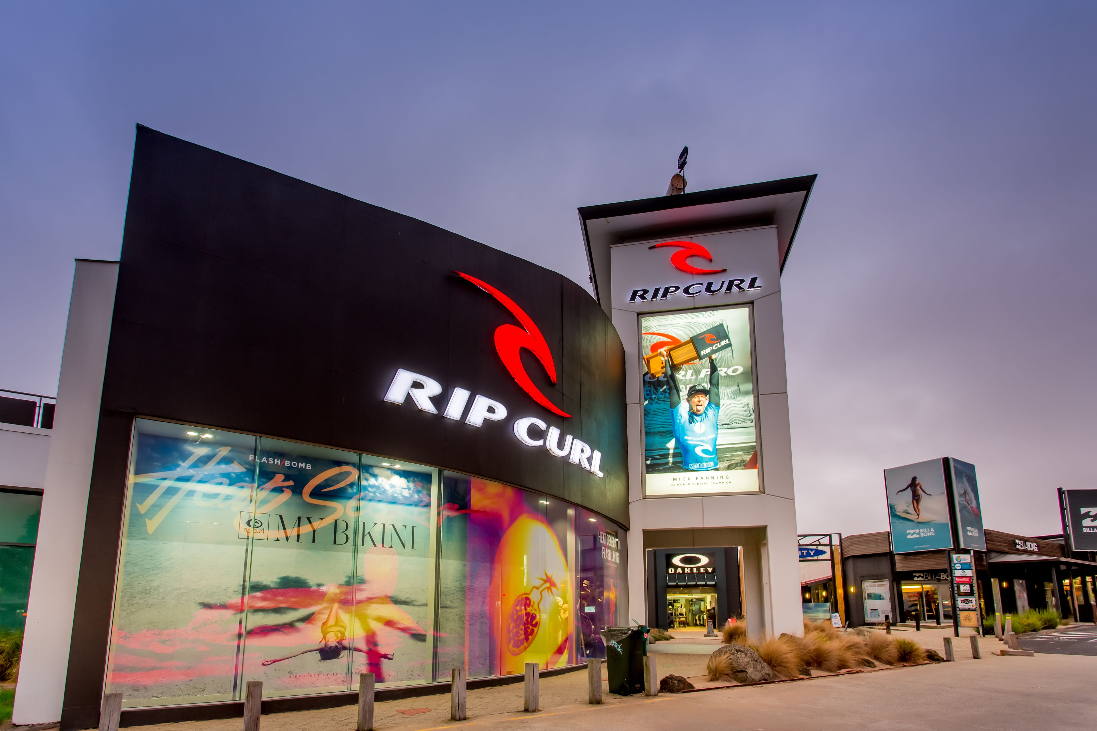 A modern building with a prominent 'Rip Curl' sign, large glass windows, and a visible storefront.
