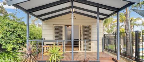 A covered outdoor area with a wooden deck, a metal railing, and a gate.