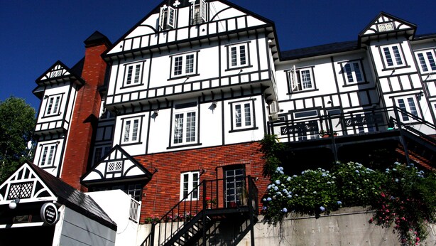En byggnad med flera våningar, uppförd i en traditionell arkitektonisk stil, med en kombination av vit och röd tegelsten, många fönster och en trappa som leder upp till de övre våningarna.