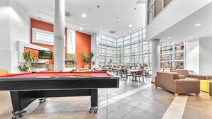 Amplo espaço interno com mesa de bilhar, assentos e grandes janelas que oferecem vista para o exterior.