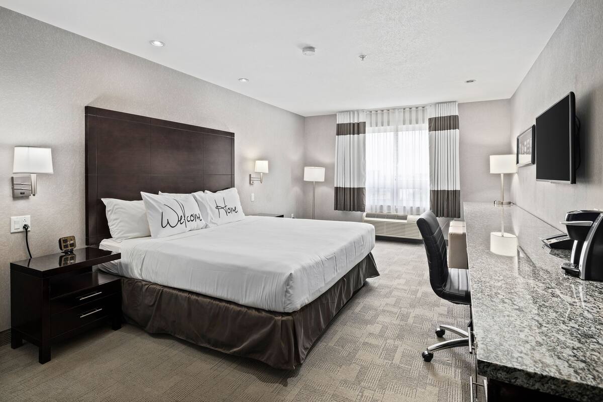 A hotel room with a large bed, a desk, and a TV.