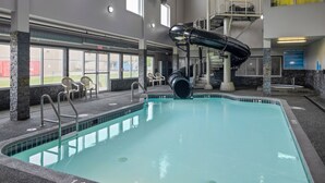 Una piscina interior con tobogán, zona de estar y un cartel que indica las normas de Whirlpool.