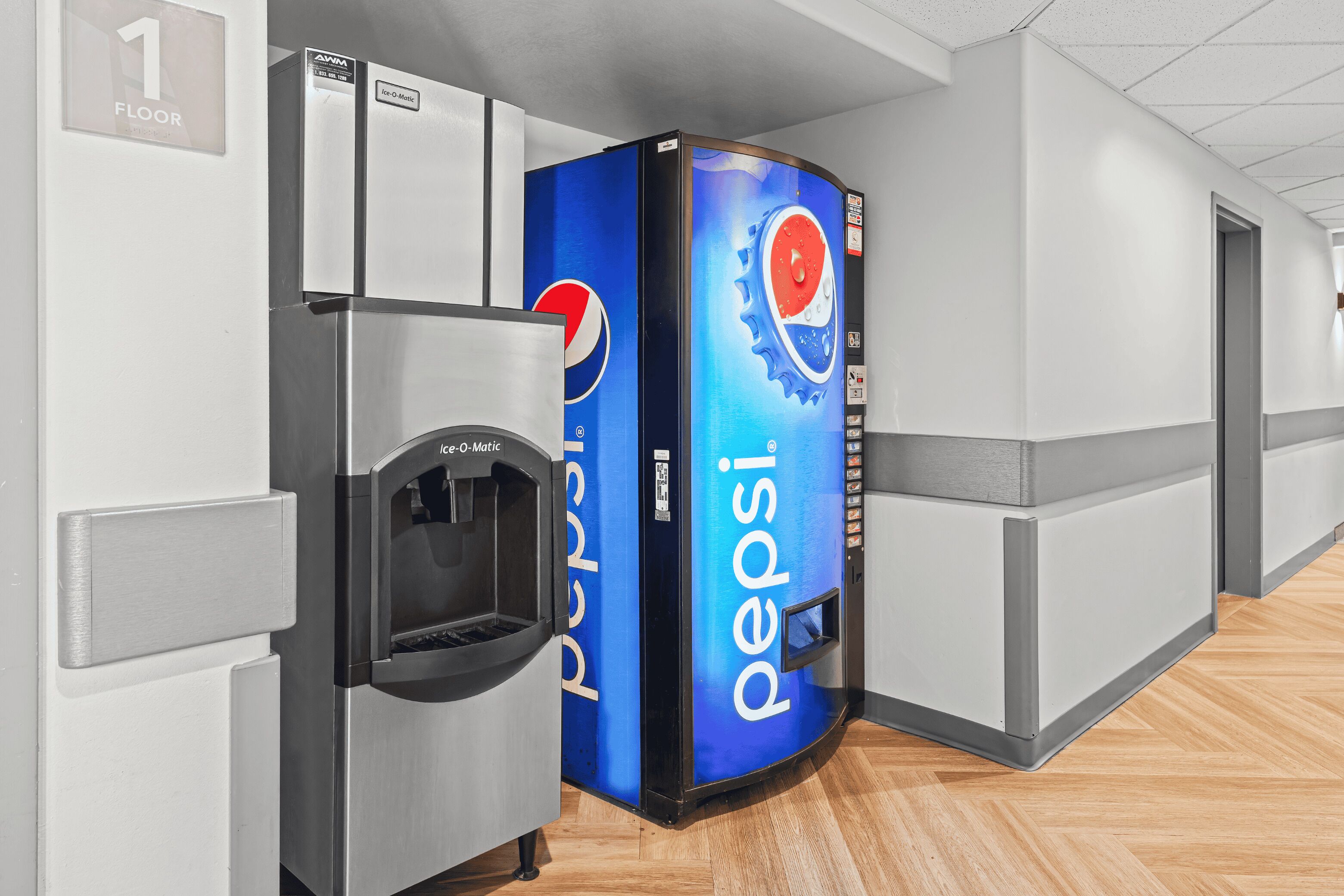 A hallway with a vending machine and a refrigerator, a floor number sign, and a wall-mounted thermostat.